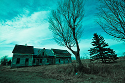 maison abandonnée dans les champs sur une photo aux teintes de bleu