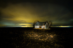light painting on old barn in mud field at night