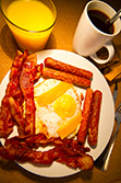 American breakfast with eggs, bacon, sausages, coffee and orange juice