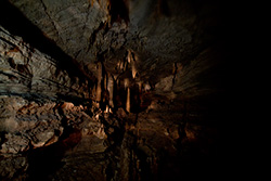 dark cave with light on stalagmites and stalactites