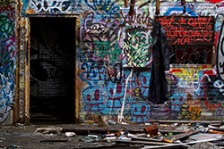 dirty black coat hanging in abandoned building, graffiti and spray cans