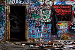 dirty coat hanging in demolished house, with doorway and graffiti