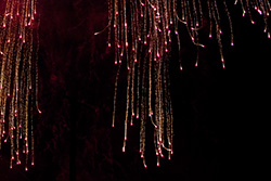 red fireworks glitter falling on dark sky