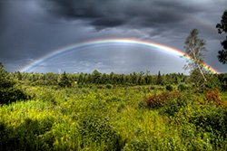 full rainbow HDR image during storm with grey clouds