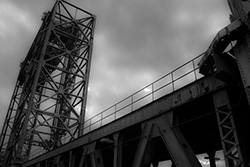 metal tower structure with steel beams bridge with cloudy sky