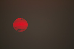 red sun with clouds on grey sky at sunset